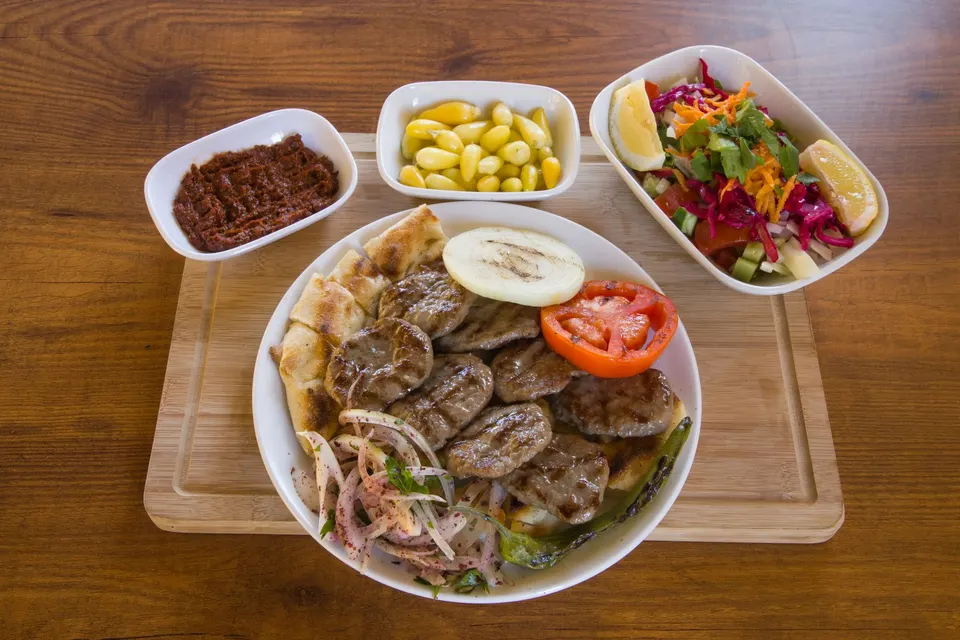 Tahta servis tablasında köfte tabağı, salata ve mezeler